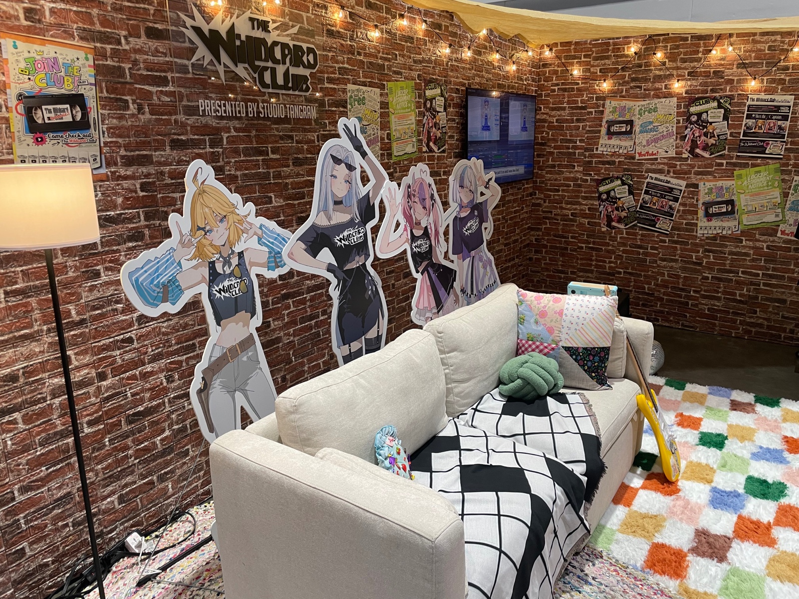 The Wildcard Club booth at OffKai Expo Gen 5 — four life-size captain standees against a brick wall with string lights, posters, and a couch